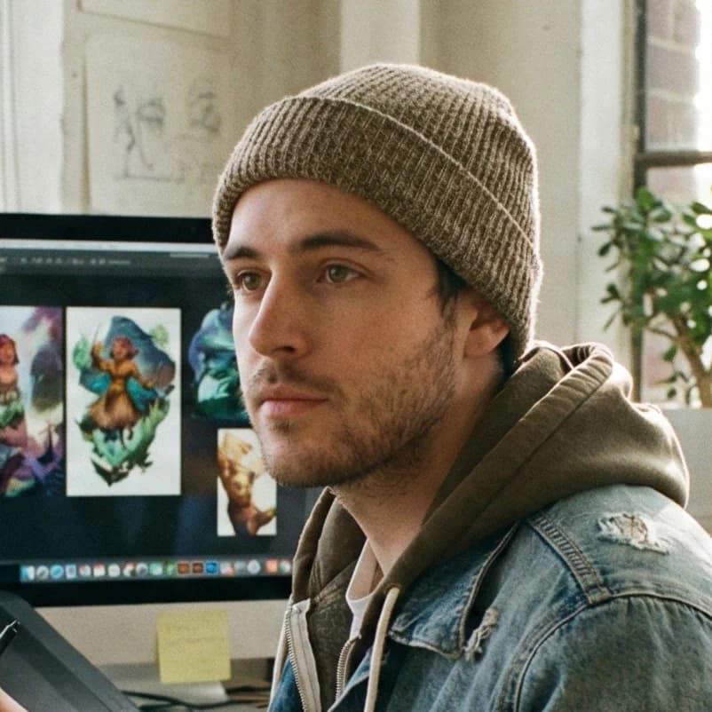 Jordan K., a freelance digital artist, working at his desk with a drawing tablet. He uses natural language prompt-based editing to speed up his creative design workflow.